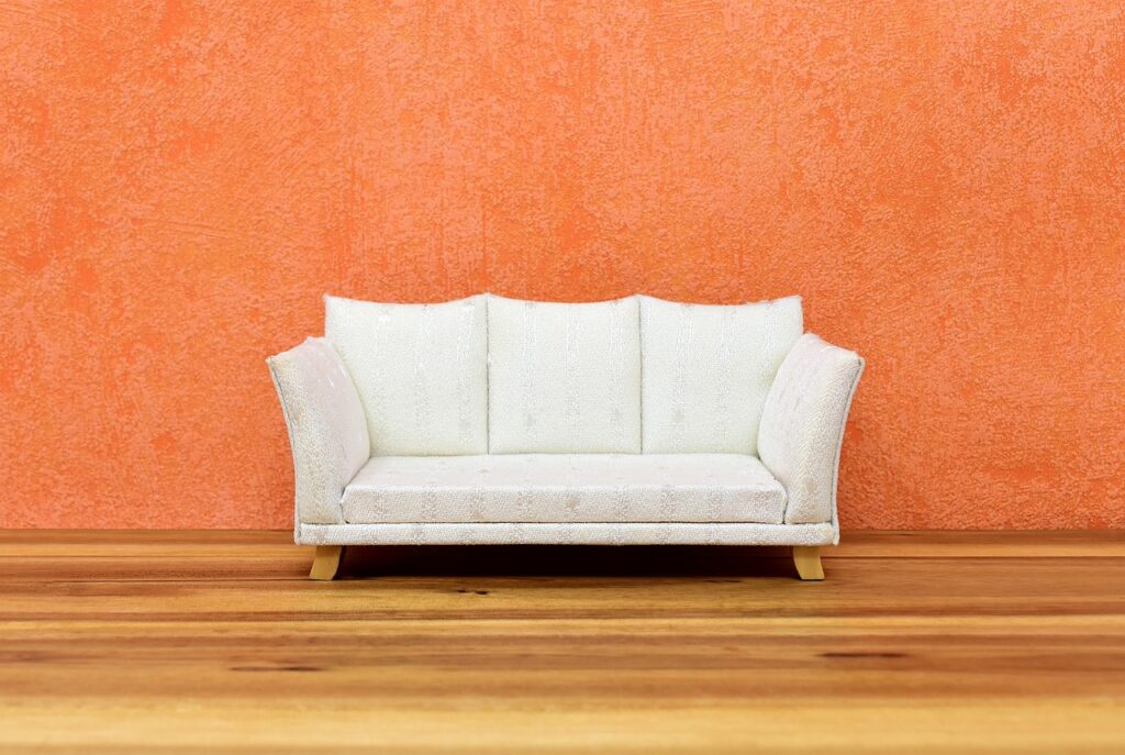 Imagen de un sofá blanco frente una pared naranja, representativa de la guía de compra para sofás.