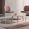 Sillas de comedor Lora con respaldo rosa y asiento gris junto a una mesa de madera