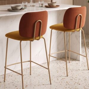 Taburetes Lora con respaldo teja, asiento mostaza y patas metálicas claras junto a una isla